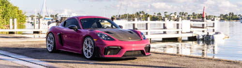 Una lussuosa auto sportiva Porsche parcheggiata su una moderna strada cittadina al... Dual UHD