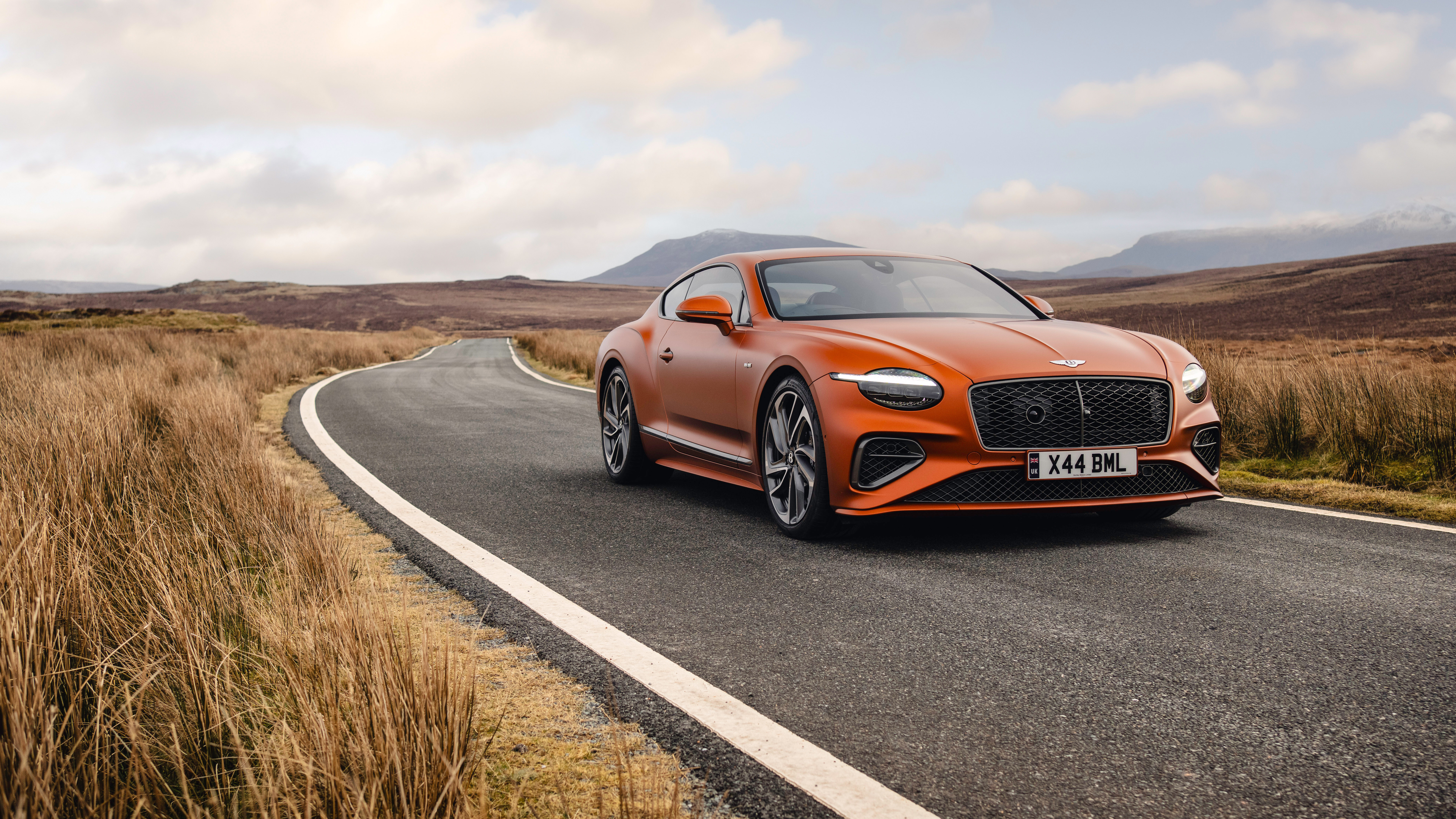 Una splendida Bentley Continental GT Speed di colore arancione acceso, che mette in risalto il suo design lussuoso e la sua imponente presenza.