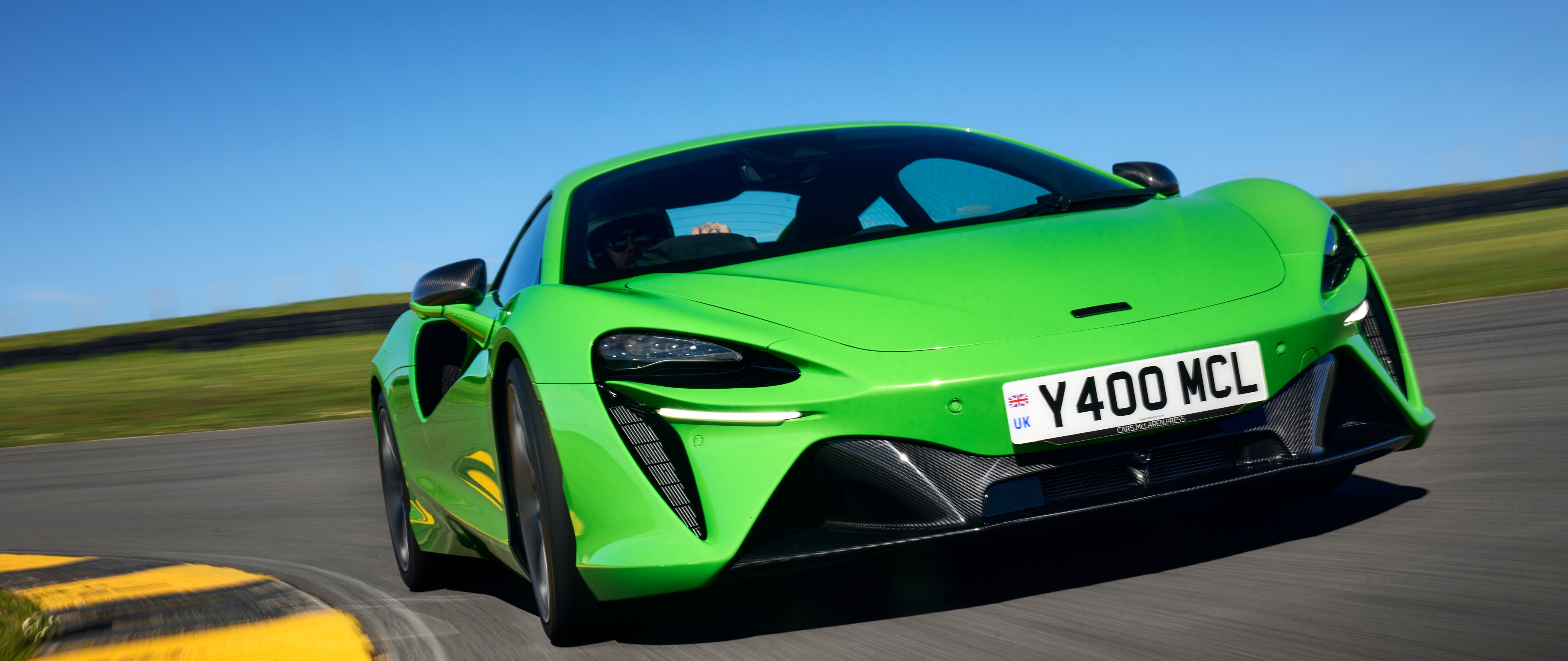 Una lussuosa supercar McLaren Artura, di un verde brillante, caratterizzata da linee aerodinamiche e una finitura lucida.