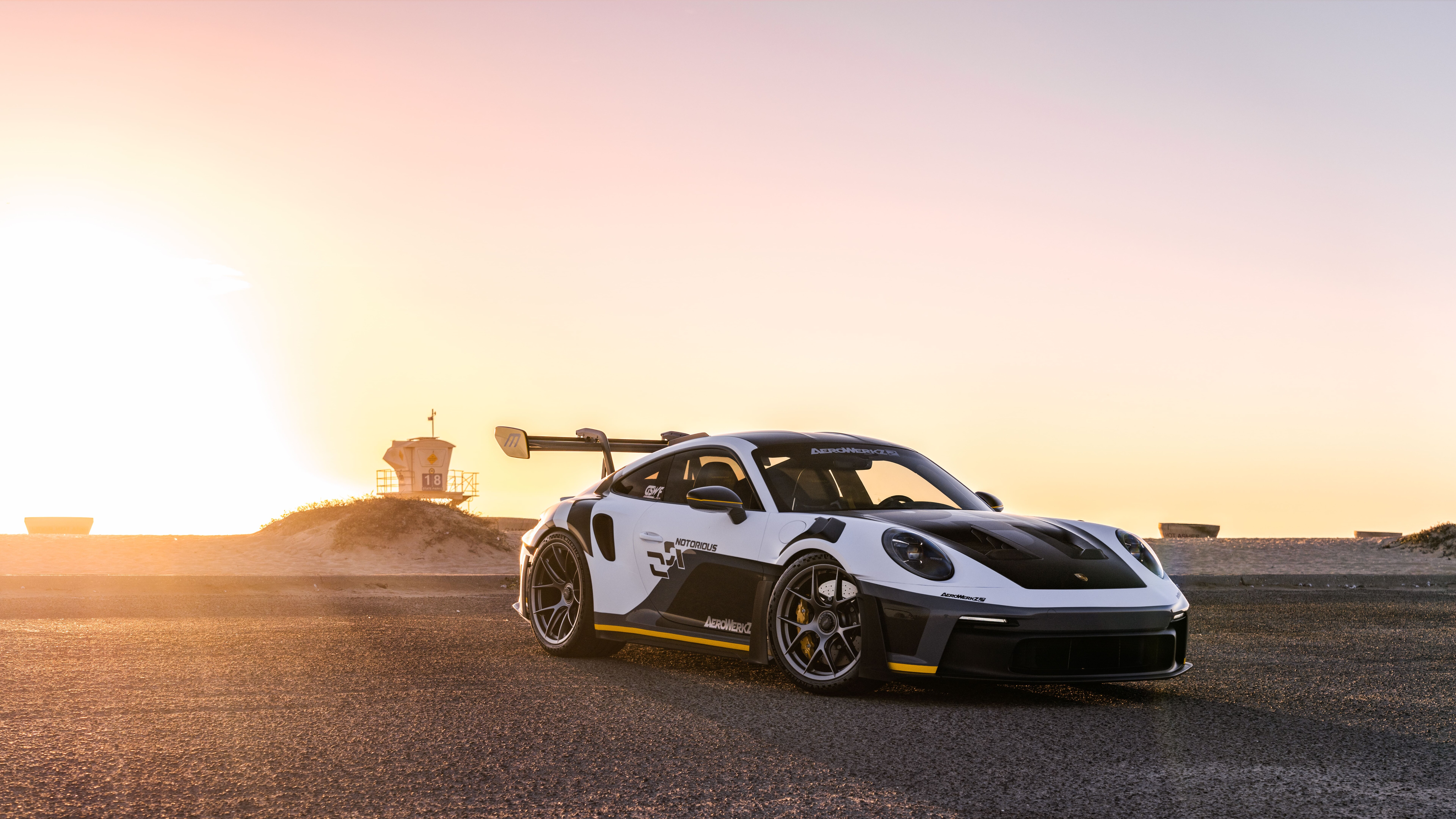 Una Porsche GT3 RS, un’auto sportiva ad alte prestazioni, caratterizzata da una carrozzeria aerodinamica dal design aggressivo e da un ampio alettone posteriore.